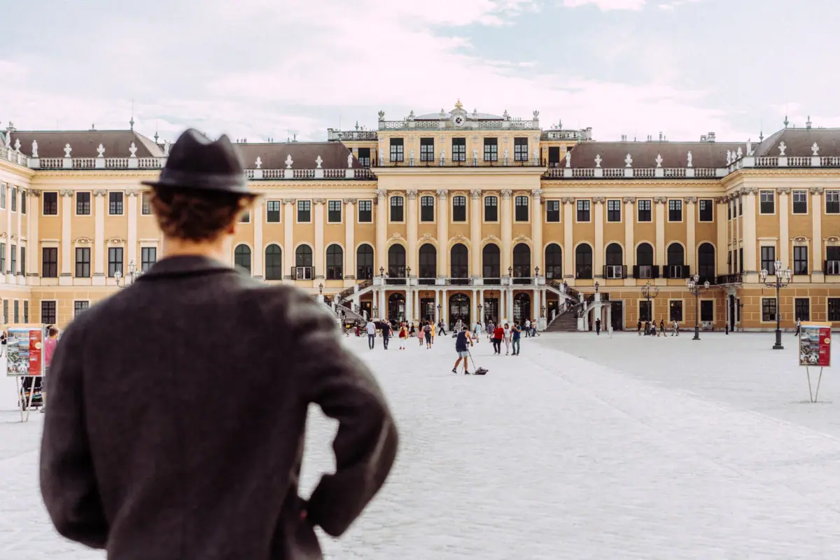 Een man met een hoed kijkt uit over het Schönbrunn Paleis in Wenen.