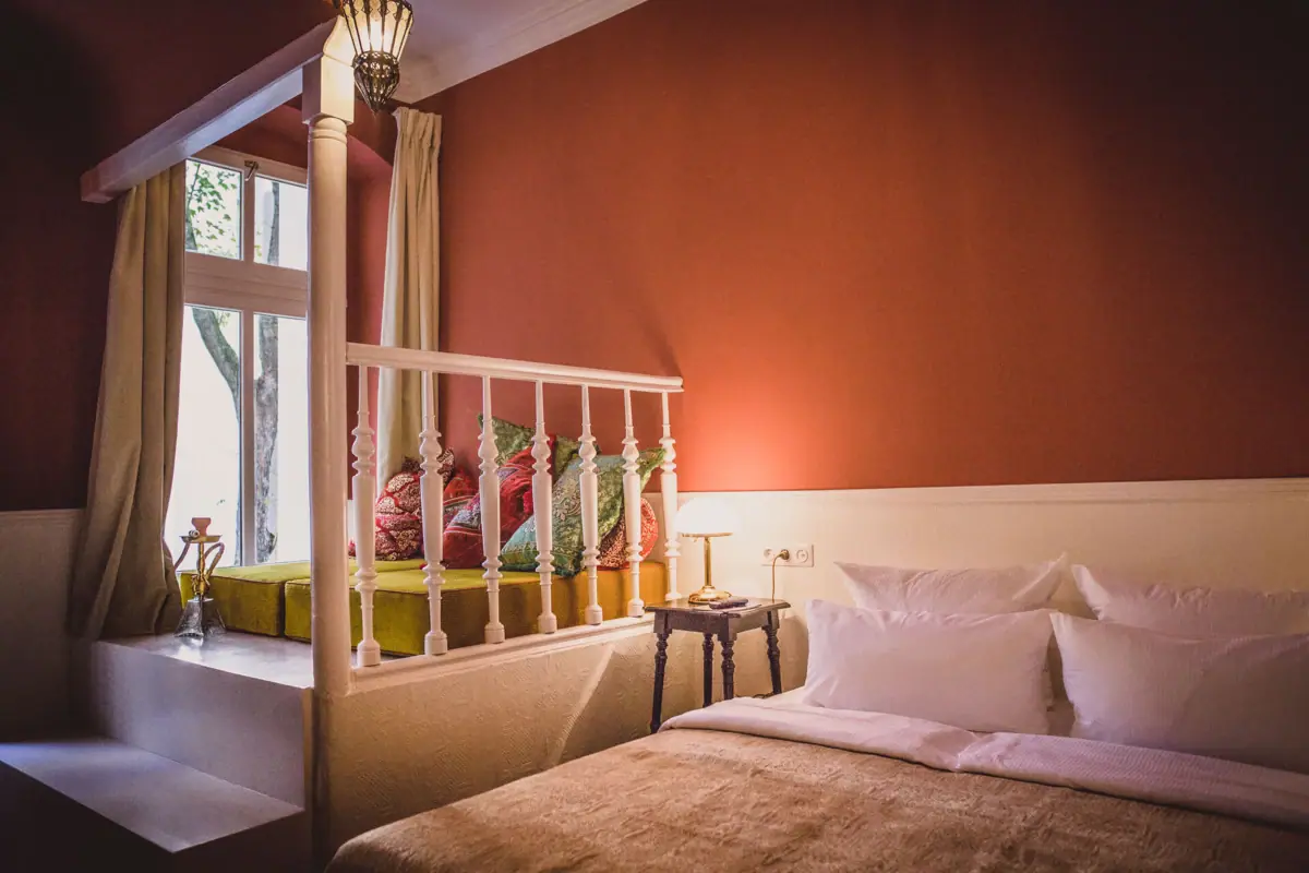 Een bed met kussens en een lamp in een kamer.