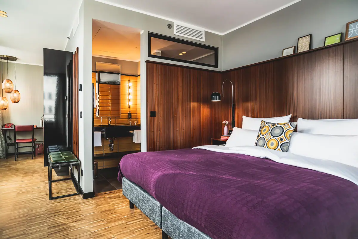 HENRI Kamers Düsseldorf Slaapkamer met paars bed en houten lambrisering.