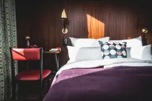 HENRI Düsseldorf Een bed met kussens en een bureau in een kamer.