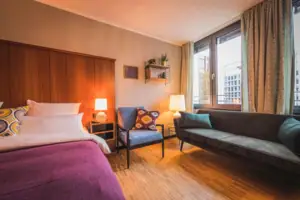 De L-Studio hotelkamer in het HENRI Hotel Düsseldorf met een bed en een bank.