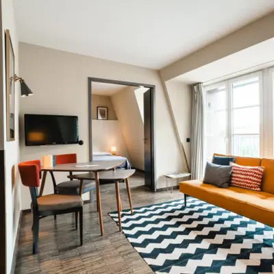 Gele bank voor een raam en tafel met twee stoelen