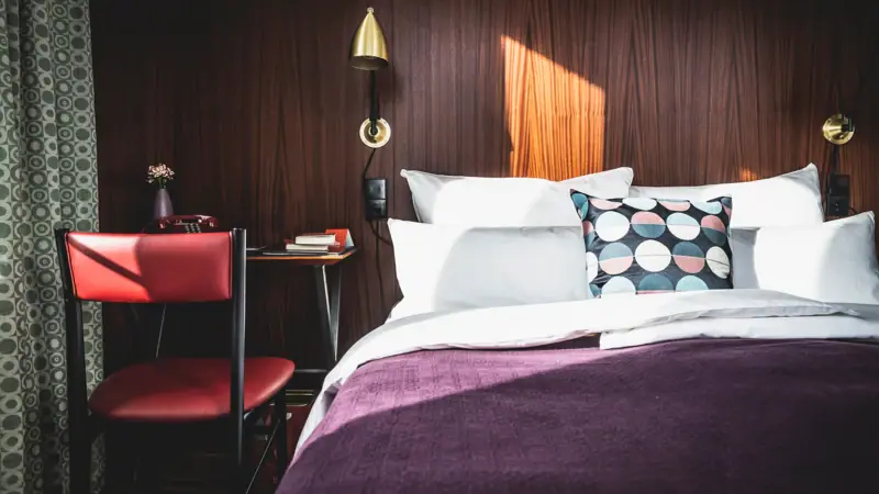 Bed met kussens en een bureau ervoor in de hotelkamer.