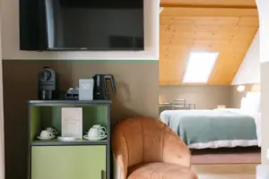 Suite in het HENRI in Garmisch-Partenkirchen Een kamer met een televisie en een stoel.