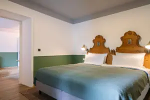 Kamers in het HENRI in Garmisch-Partenkirchen Een bed met twee houten hoofdeinden in een kamer.