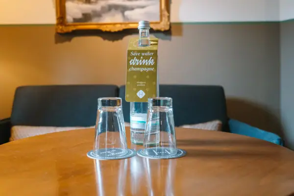 Waterfles en glazen in het HENRI Hotel in Garmisch-Partenkirchen Een fles en glazen op een tafel in een hotelkamer van het HENRI Hotel in Garmisch-Partenkirchen.