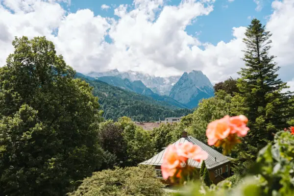 Uitzicht vanaf het balkon van het HENRI Hotel Garmisch-Partenkirchen met bloemen en bergen op de achtergrond.