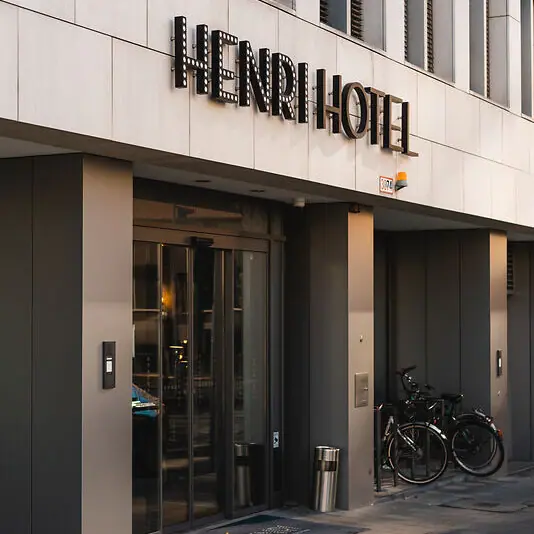 Entree HENRI Hotel Düsseldorf Een gebouw met een bord erop.