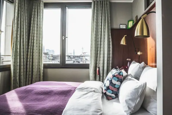 Een bed met kussens en een lamp in een kamer met ramen.