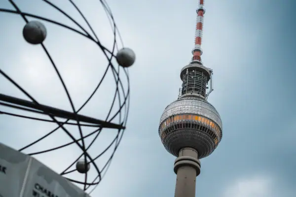 Alexanderplatz in Berlijn met een hoge ronde toren voor een blauwe lucht met wolken.