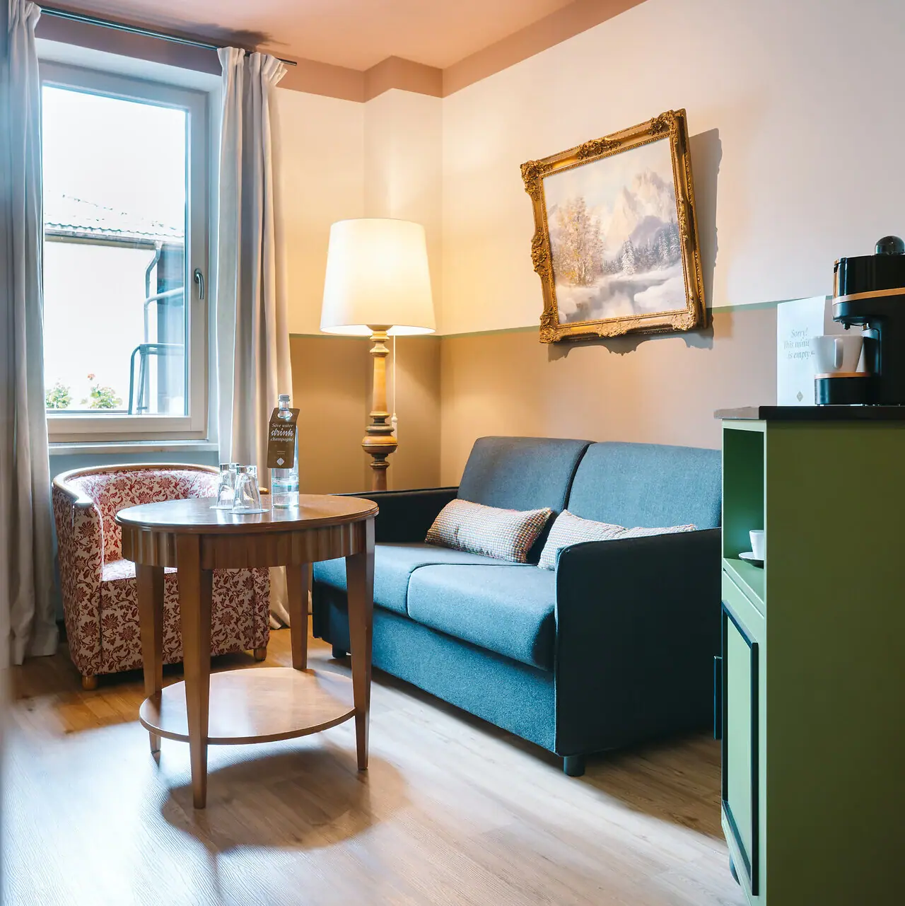 Woongedeelte in een hotelkamer in het HENRI Garmisch-Partenkirchen met een bank en een tafel.