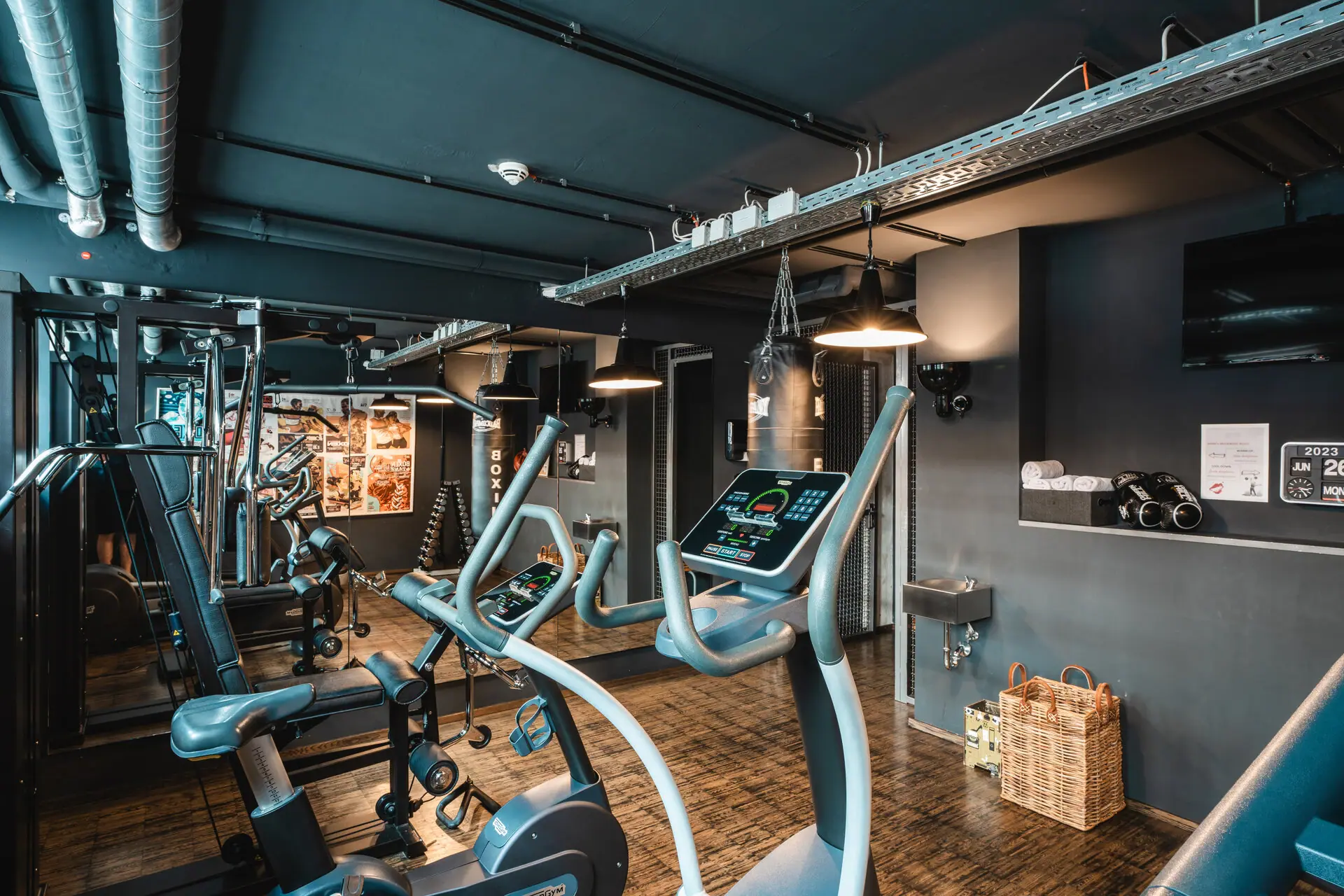 Een ruimte met fitnessapparaten en een houten vloer.