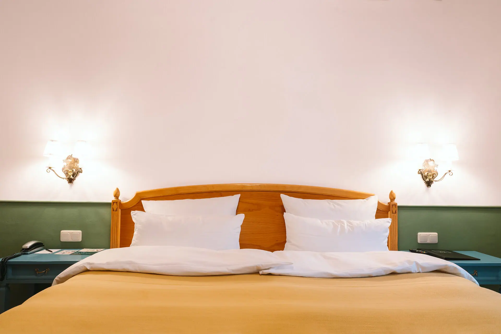 Hotelkamer HENRI Hotel Garmisch-Partenkirchen Een bed met witte kussens en lampen aan de muur in een hotelkamer in het HENRI Hotel Garmisch-Partenkirchen.