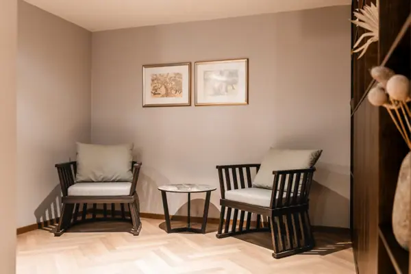 Een kamer met stoelen en een tafel, ingericht met een bank, een houten vloer en een salontafel.