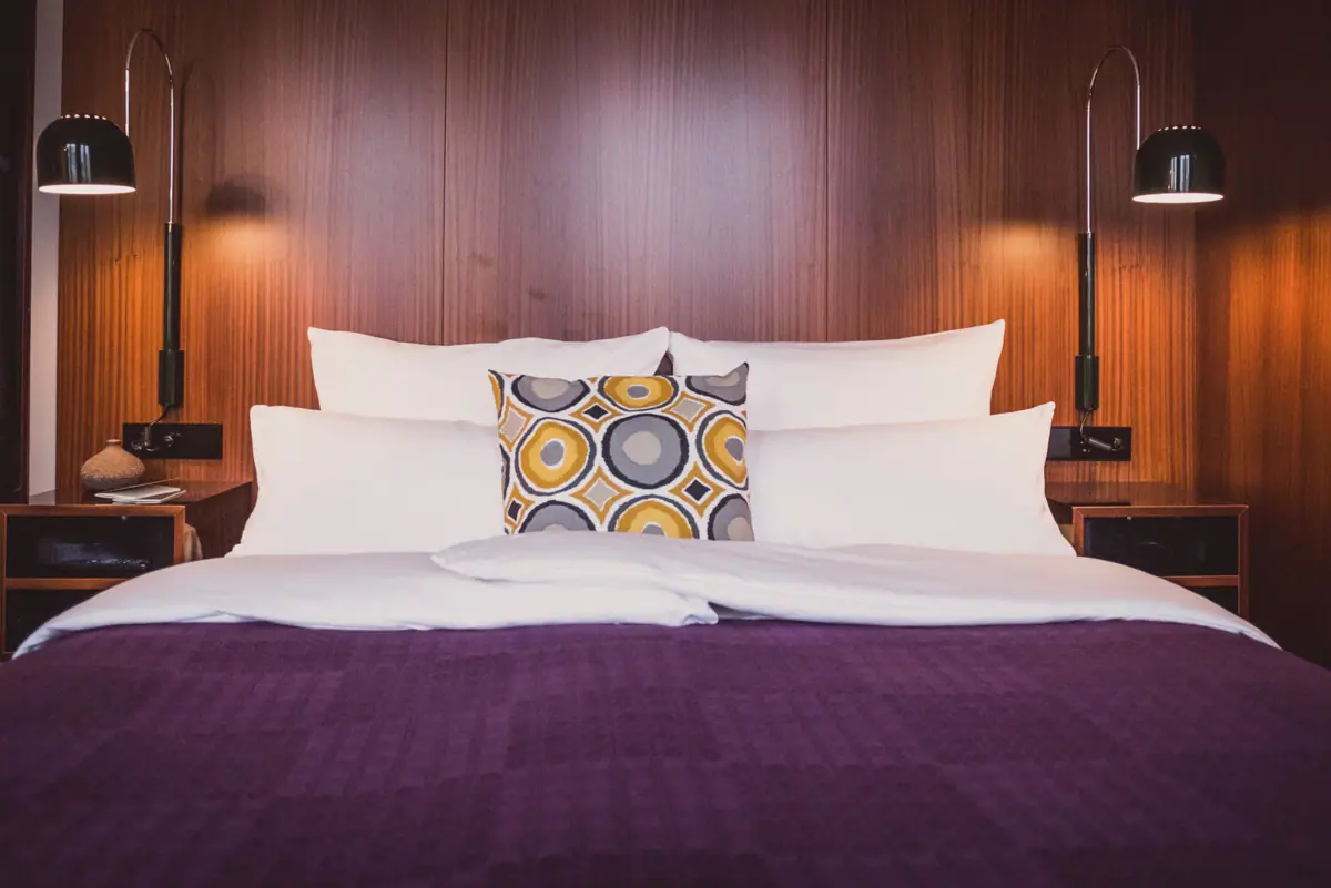 Een bed met kussens en een lamp.