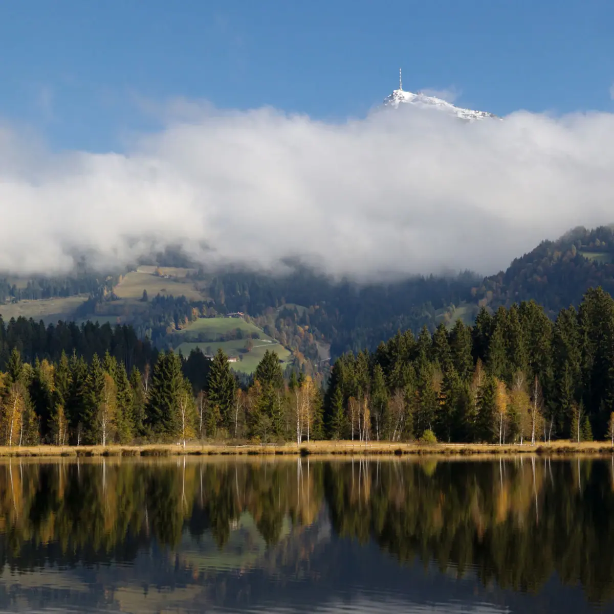 Kitzbühel Schwarzsee Een meer met bomen en bergen op de achtergrond.