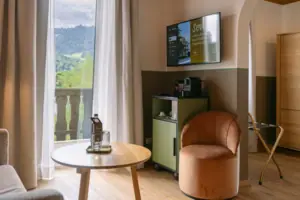 Woonruimte in het HENRI in Garmisch-Partenkirchen Een kamer met een televisie en een stoel.
