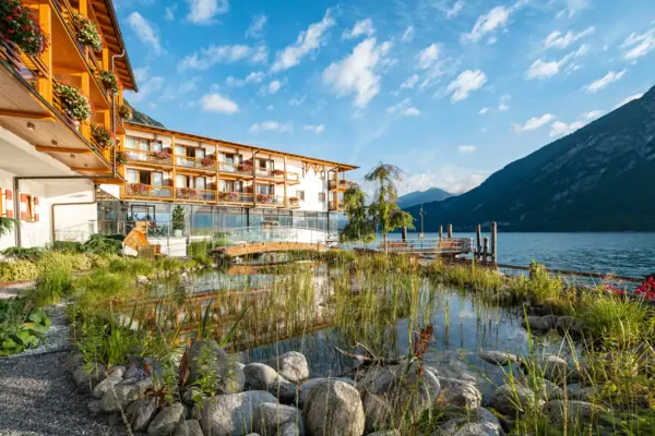 aja Fürstenhaus aan de Achensee het aja Fürstenhaus aan het Achenmeer met een vijver en bergen op de achtergrond.