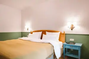 Een hotelkamer in het HENRI Hotel Garmisch-Partenkirchen met een bed voor een groen-witte muur.