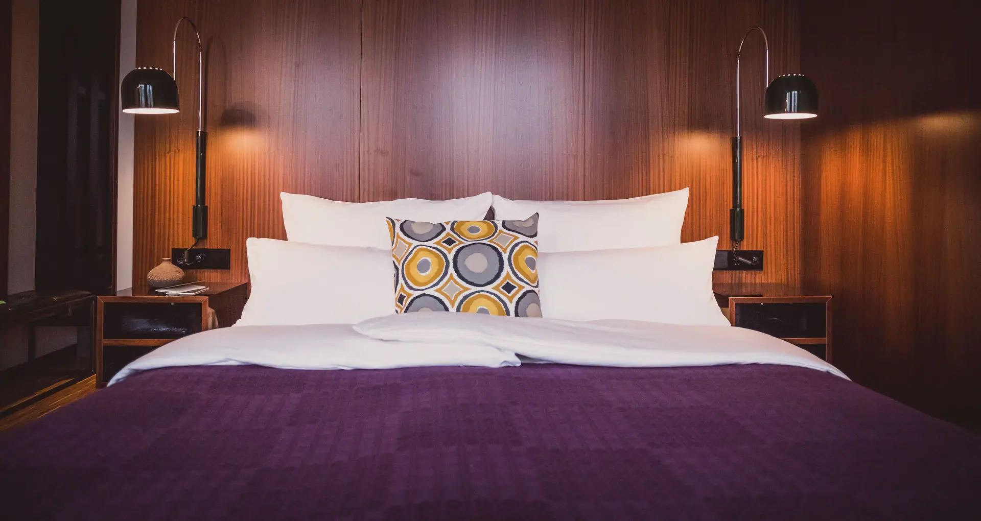 HENRI Düsseldorf Een bed met kussens en een lamp.