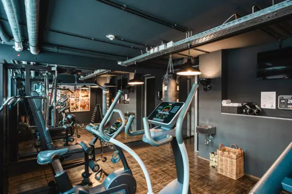 Een ruimte met fitnessapparaten en een houten vloer.