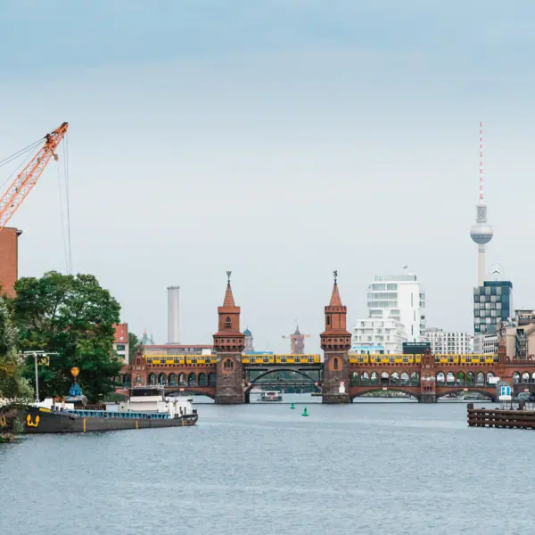 Rondvaart op de Spree in Berlijn Een brug over een rivier met een kraan en een stad op de achtergrond.