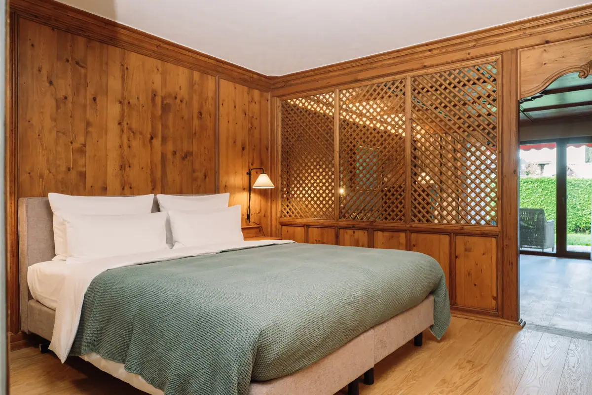 Bed met groene sprei voor een met hout beklede muur