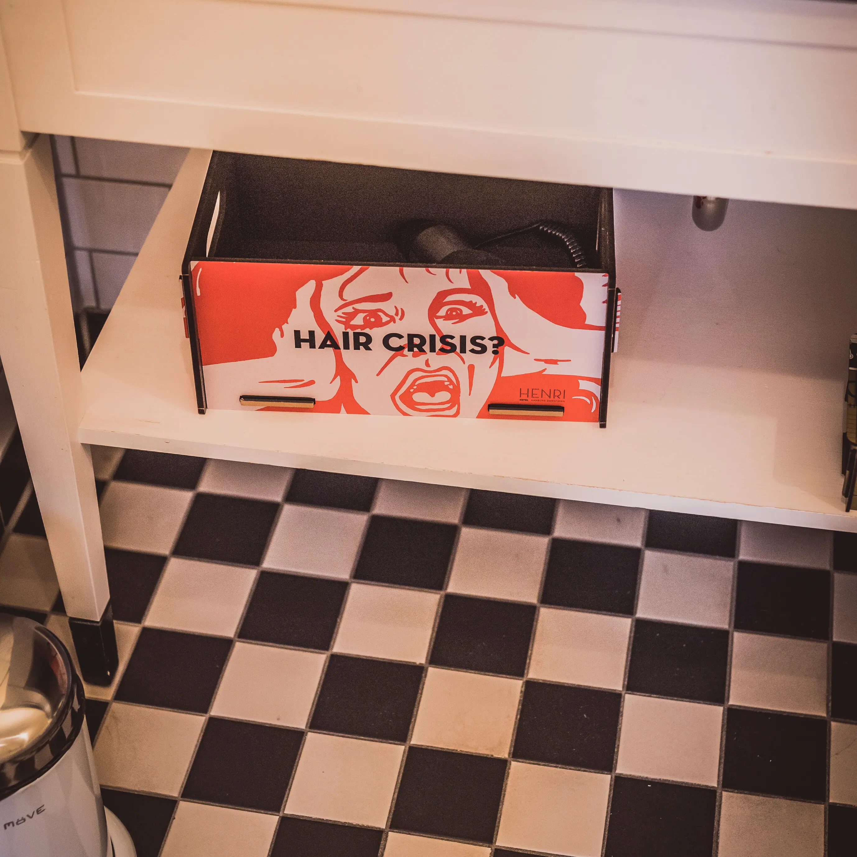 Kleurrijke doos met haardroger op een badkamerplankje