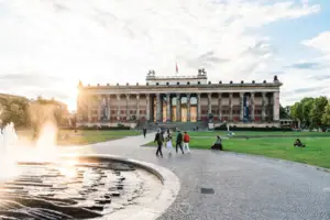 De imposante zuilengevel van het Altes Museum in Berlijns Lustgarten bij laagstaande zon met een fontein op de voorgrond