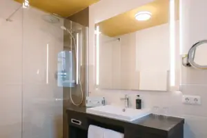 Een badkamer met wastafel en spiegel in het HENRI Hotel Garmisch-Partenkirchen.