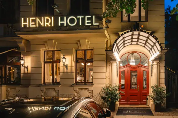 De verlichte gevel en ingang van het HENRI Hotel Berlin in een historisch gebouw in Wilhelminische stijl bij nacht.