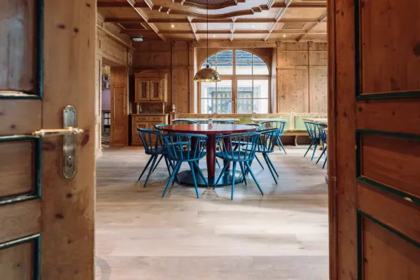 Een kamer met een ronde tafel en blauwe stoelen.