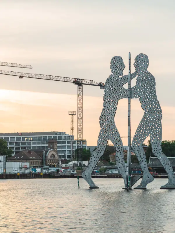 Molecule Men Berlijn Grote metalen pilaar met mannen in het water en kranen op de achtergrond.