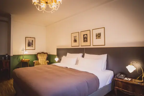 HENRI Wenen Kamers Een bed met een kroonluchter en foto's aan de muur.