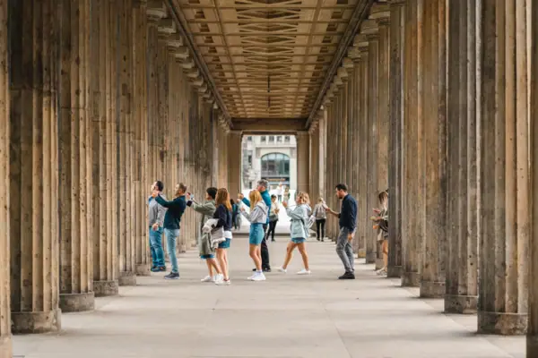 Perspectief op de historische zuilengang op het Berlijnse Museumeiland met toeristen tussen de imposante stenen zuilen.