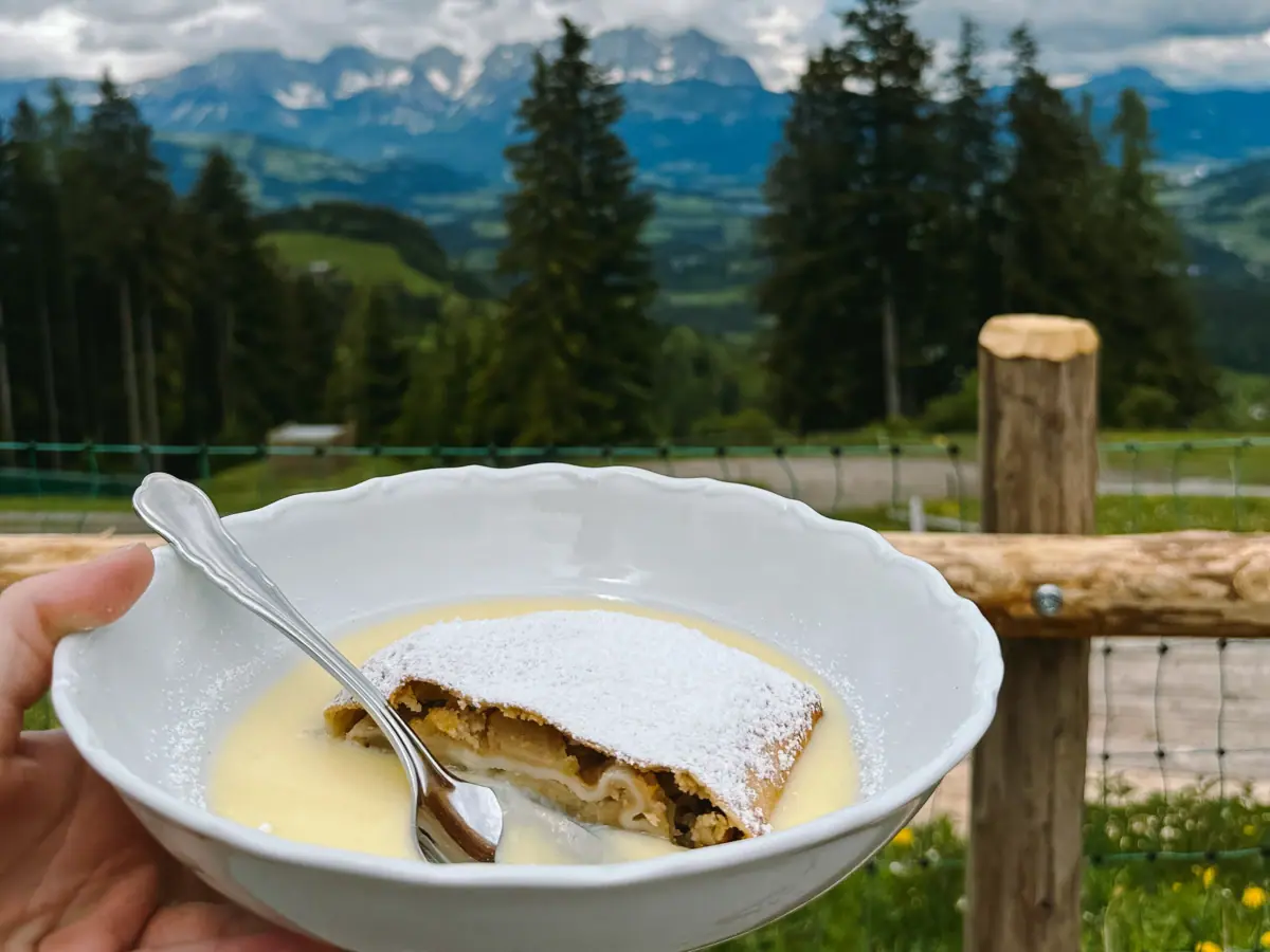 Eén hand houdt een kom met eten en een lepel vast.