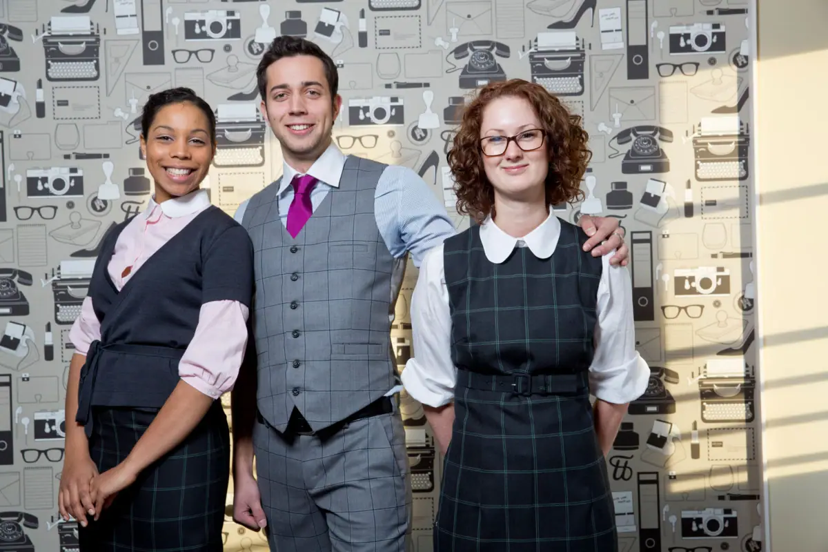 HENRI HH Medewerkers Een groep mensen poseert voor een foto, lachend en in formele kleding.