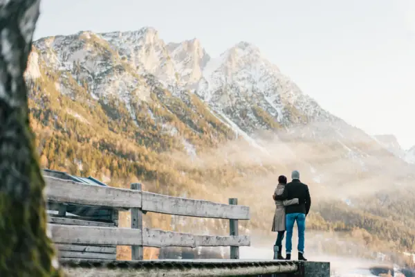 Een man en een vrouw staan op een steiger met uitzicht op een bergketen.