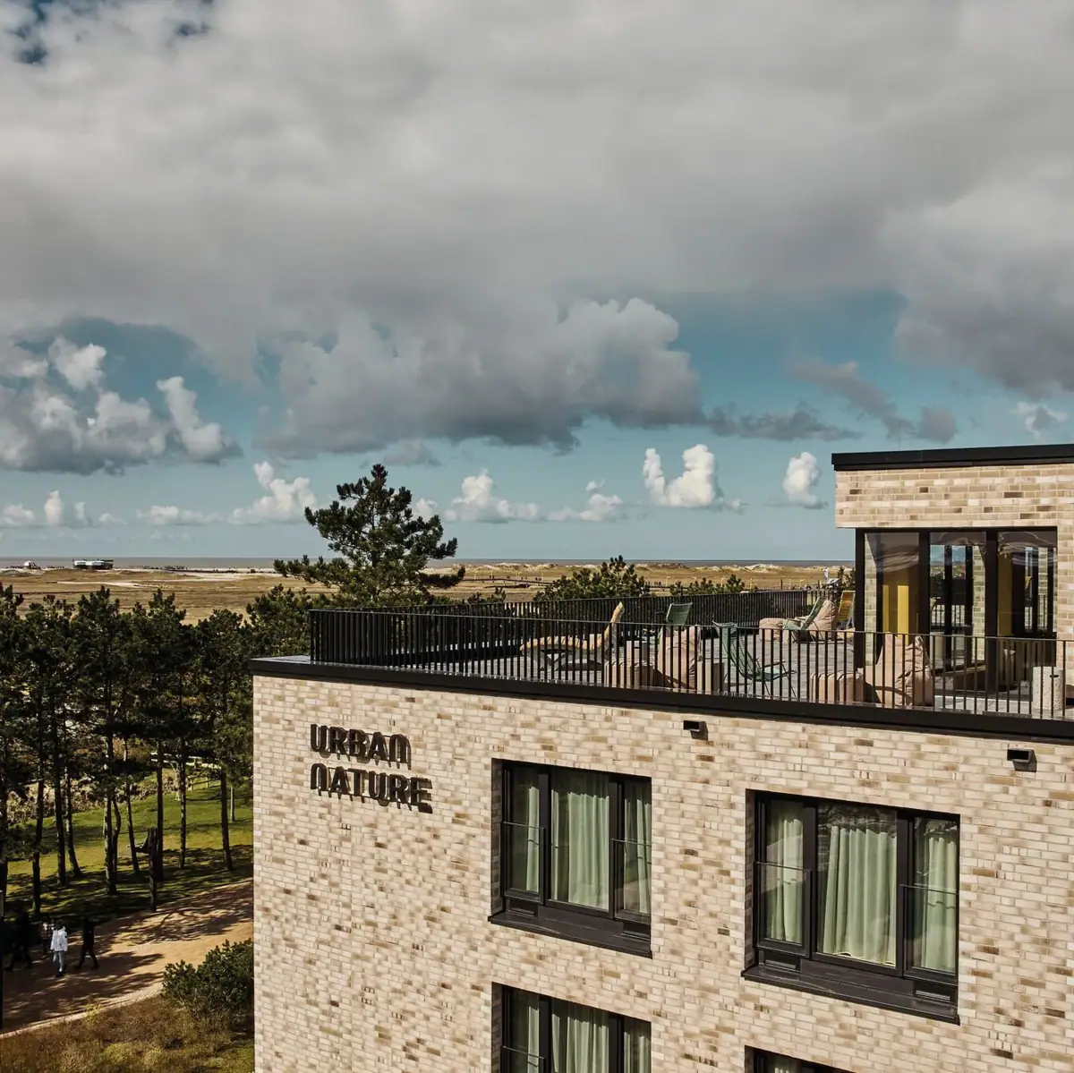 Stadsnatuur St. Peter-Ording Een gebouw met een balkon dat uitkijkt op een strand.