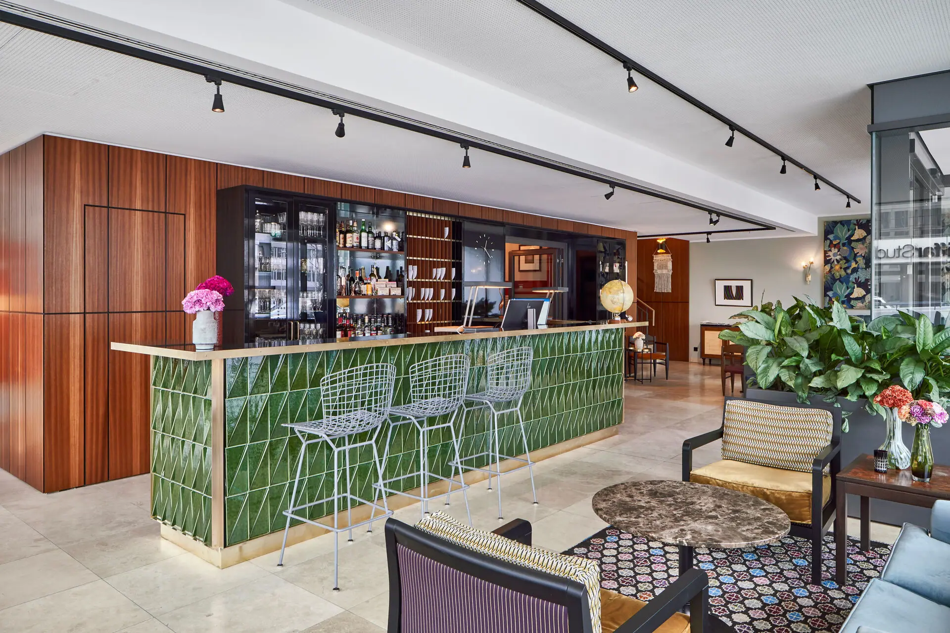 HENRI Düsseldorf Bar met groene tegels en stoelen.