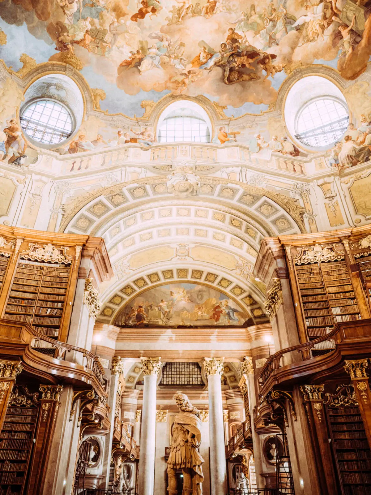 Een grote, rijk versierde bibliotheek met een plafondfresco.