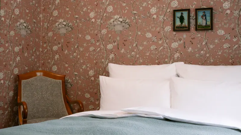 Een bed met kussens en een stoel in een kamer.