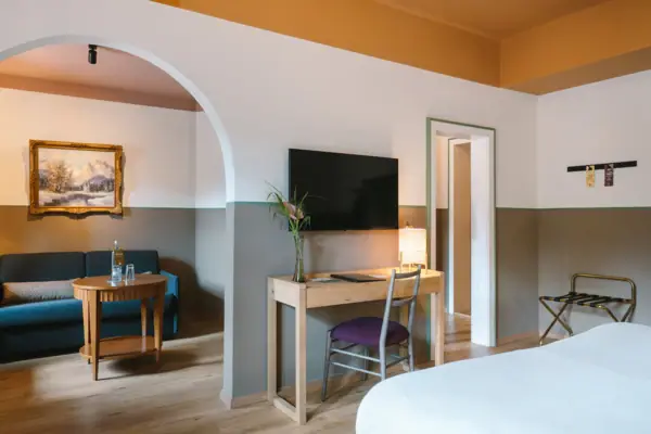 Hotelkamer HENRI Hotel Garmisch-Partenkirchen Een ruime hotelkamer in het HENRI Hotel in Garmisch-Partenkirchen met een doorgang van de slaapkamer naar de woonkamer.