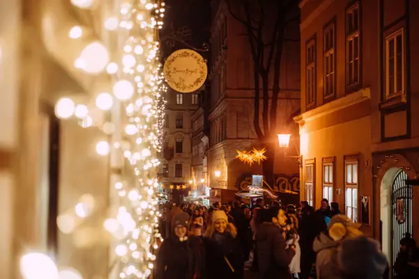 Kerstverlichting Een menigte loopt door een straat die verlicht wordt door kerstverlichting.