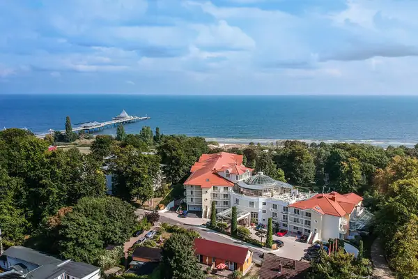 Strandidyll Heringsdorf Groot gebouw met een pier op de achtergrond.