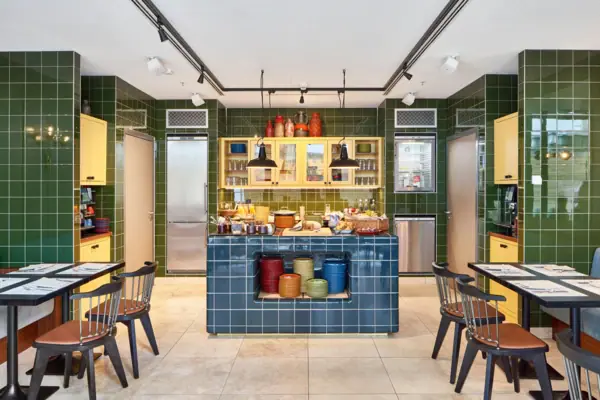 Keuken met groene tegels, een blauwe tegelbar en stoelen.