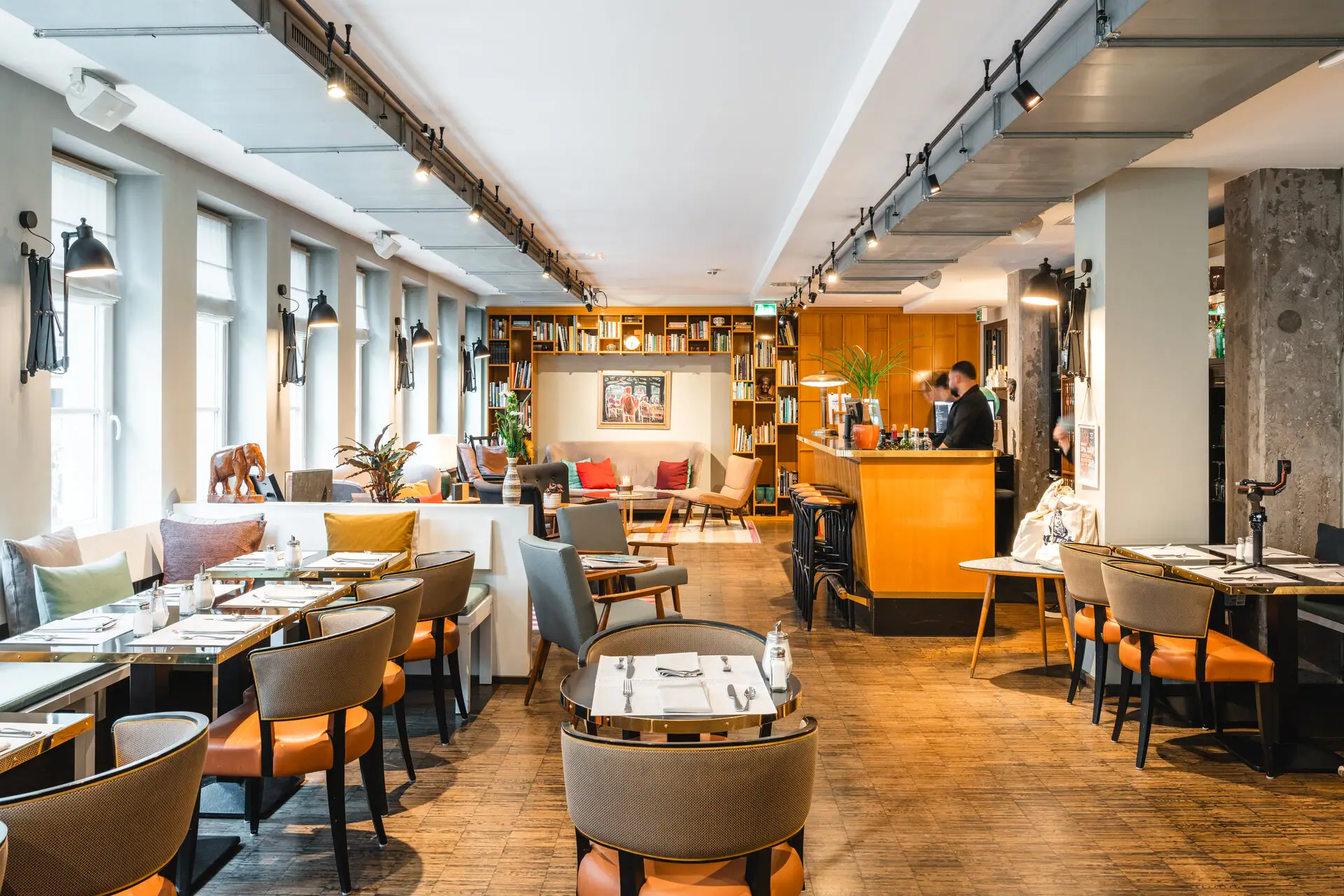 Loungeruimte in het HENRI Hotel Hamburg Zithoek met tafels en stoelen.