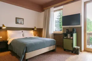 Kamer met balkon in het HENRI in Garmisch-Partenkirchen Een bed in een slaapkamer met een stijlvol interieur.