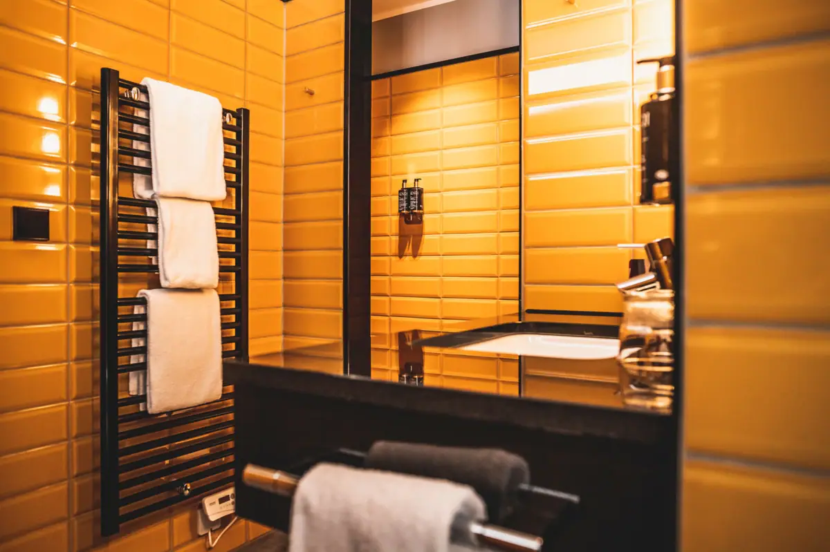 Badkamer met gele betegelde muren en een spiegel