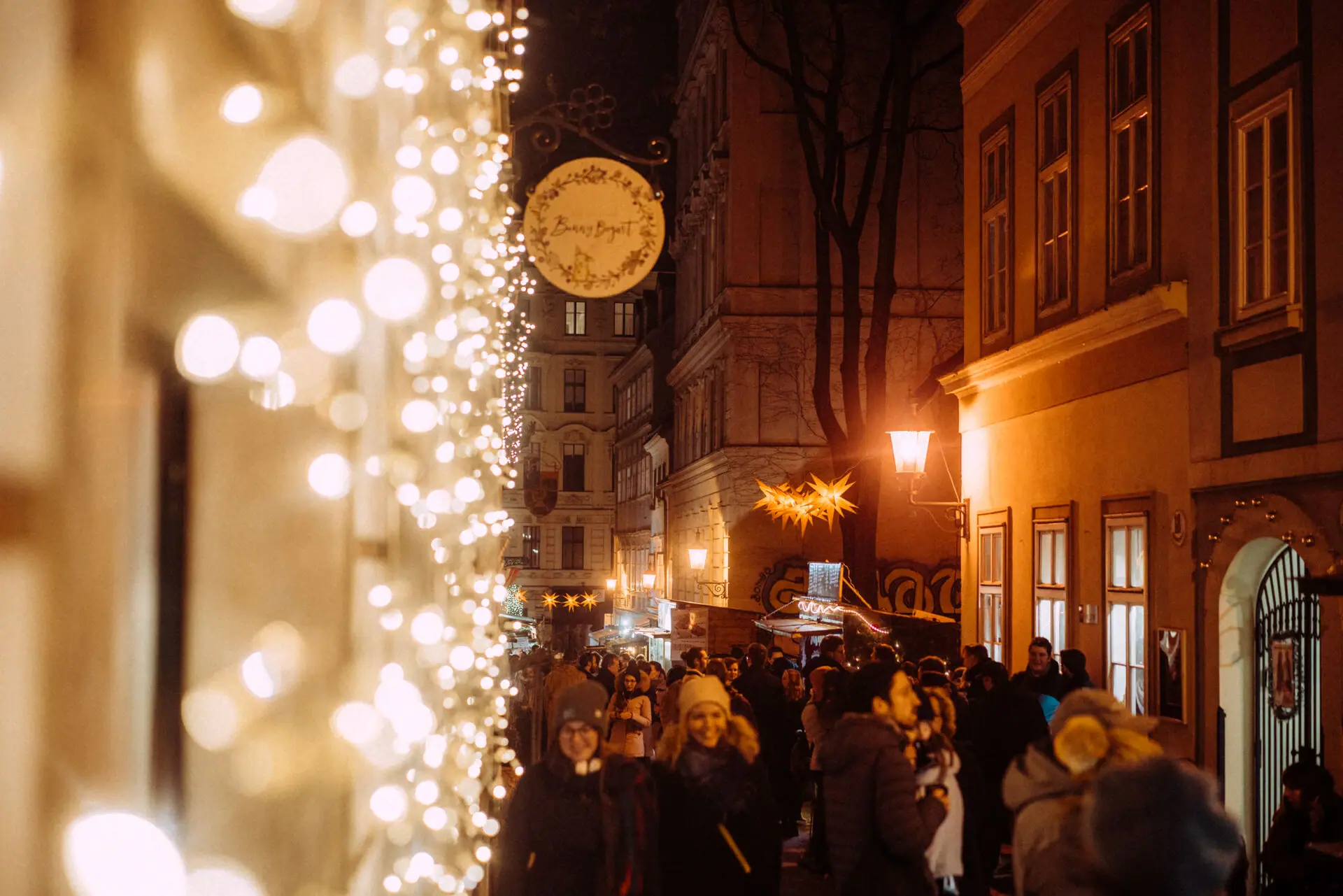 Kerstverlichting Een menigte loopt door een straat die verlicht wordt door kerstverlichting.